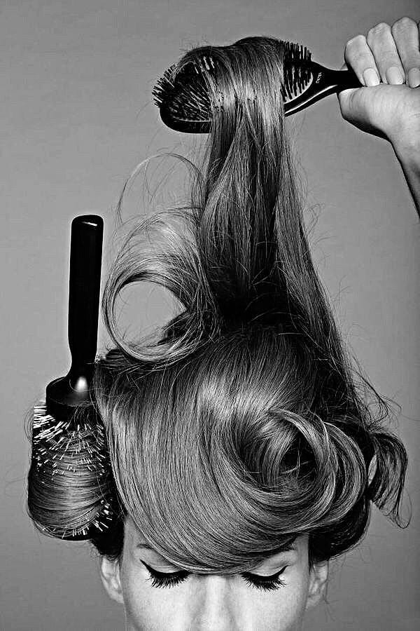 Black and white shot of long hair being styled with round brushes