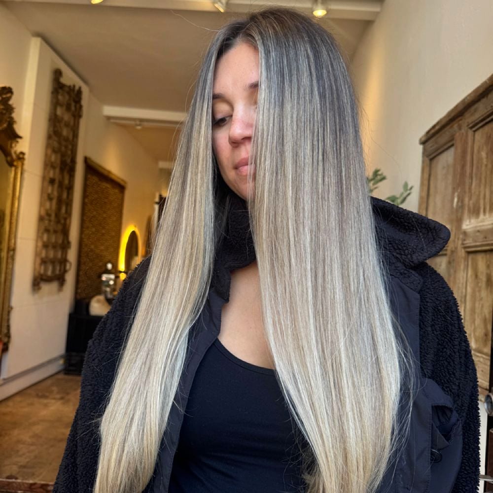 Long straight blonde and grey balayage, styled in a salon hallway